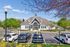 Charming residential building with elegant gabled roof, lush landscaping, and ample parking, showcasing vibrant spring foliage.