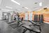 Modern fitness center with state-of-the-art exercise machines, vibrant orange wall mural, and ample natural light.