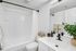 Elegant modern bathroom featuring a pristine white bathtub, stylish black fixtures, and a lush green plant accentuating a calming atmosphere.