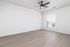Bright, spacious room with sleek wood flooring and modern ceiling fan, offering ample natural light through large windows.