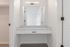Bright and modern bathroom vanity with sleek white countertop and built-in mirror, offering ample space for daily routines.
