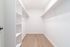 Spacious walk-in closet with elegant wooden flooring and ample shelving.