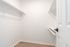 Bright and spacious walk-in closet with sleek white shelving and elegant wooden floors.