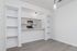 Chic and modern apartment kitchen featuring sleek white cabinetry, stainless steel appliances, and open shelving against a minimalist backdrop.
