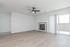 Bright and spacious living room with modern wood flooring, elegant marble fireplace, and sliding glass doors opening to a sunlit patio.