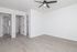 Bright and airy apartment room with sleek wood flooring, modern ceiling fan, and convenient bathroom access.