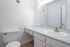 Sleek bathroom featuring a modern granite countertop, stylish mirror, and pristine white fixtures for a refreshing atmosphere.