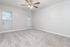 Spacious bedroom featuring plush carpeting, abundant natural light from two windows, and a modern ceiling fan.