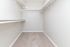 Spacious walk-in closet with sleek white shelving and plush carpeting, offering ample storage potential and modern charm.