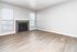 Elegant living room with pristine hardwood floors and a cozy fireplace, featuring abundant natural light from large windows.