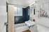 Modern bathroom featuring chic navy tiles, a sleek white sink, and stylish wall art, creating a serene and elegant atmosphere.