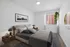 Elegant bedroom featuring a plush bed, stylish decor, large window with blinds, and a vibrant hanging plant for a serene atmosphere.