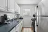 Contemporary kitchen featuring sleek white cabinets, modern appliances, and abundant natural light through a window with blinds.