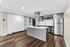 Modern kitchen featuring sleek cabinetry, stainless steel appliances, and a central island with dark wood flooring.