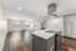 Modern open-concept apartment with sleek kitchen island, spacious wooden flooring, and ample natural light from large windows.