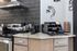 Modern kitchen corner featuring a sleek coffee bar with a stylish backsplash, stainless steel appliances, and an organized coffee station.