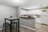Modern kitchen with sleek white cabinets, elegant countertops, and a cozy dining area with stylish seating in an inviting apartment setting.