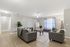 Inviting living room with chic gray sofas, a large mirror, and abundant natural light through floor-length windows.