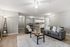 Modern open-concept living room featuring sleek gray sofas, a stylish coffee table, and a contemporary kitchen in a bright, inviting space.