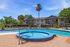 Inviting apartment complex with a sparkling pool and relaxing hot tub, surrounded by lush greenery and modern accommodations.