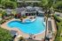 Breathtaking aerial view of a luxurious pool area with a unique design, surrounded by palm trees and modern amenities, creating an ideal relaxation spot in a vibrant community.