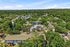 Vibrant aerial view of a serene apartment complex surrounded by lush greenery, featuring a central swimming pool and charming residential buildings.