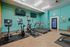 Modern apartment gym with state-of-the-art exercise bikes, treadmills, and a vibrant teal interior.