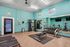 Inviting fitness center with modern gym equipment, vibrant teal walls, and large mirrors for an energized workout experience.