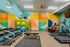 Vibrant home gym with colorful mural, equipped with treadmills, dumbbells, and exercise bikes for a dynamic workout experience.