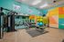 Vibrant, fully-equipped gym with modern fitness machines, colorful wall mural, and essential workout equipment.
