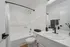Modern bathroom featuring a sleek white vanity with matte black fixtures, a spacious bathtub with a curved shower rod, and elegant accessories for a stylish touch.