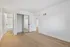 Bright and spacious bedroom with sleek wooden flooring, mirrored closet doors, and an ensuite bathroom entrance.