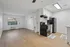 Charming open-concept living space featuring sleek hardwood floors, modern kitchen with black appliances, and bright natural light from the window.