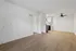 Spacious open-plan living area with stylish light wood flooring, modern ceiling fan, and bright kitchen alcove.