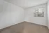 Bright bedroom with plush carpet and large window offering scenic views of lush greenery.