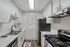 Modern kitchen with sleek white cabinets, stainless steel appliances, and elegant marble countertops, beautifully illuminated by natural light through window blinds.