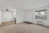 Bright and inviting living space with plush carpet and modern ceiling fan; window with blinds offers natural light and neighborhood view.