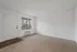Bright and airy living room with plush carpet, large window view, and modern wall-mounted air conditioning.