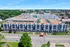 Aerial view of modern apartment complex with sleek design and lush greenery, situated in a vibrant urban setting.