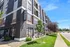 Modern apartment exterior with striking architectural design, lush green landscaping, and vibrant urban setting.
