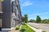 Chic urban apartment building with contemporary design, featuring lush green landscaping and a vibrant neighborhood setting.