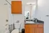Modern bathroom with elegant wooden cabinets, sleek granite countertop, and pristine white fixtures.