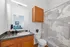 Bright and inviting bathroom with modern fixtures, featuring a large mirror, elegant wooden cabinets, and artful shower curtain.