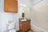 Modern bathroom with clean white tiles, elegant wooden cabinetry, and a sleek countertop basin.
