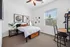 Cozy bedroom with modern decor featuring a stylish bed, elegant artwork, and a functional desk by the window, bathing the room in natural light.