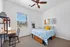 Bright and inviting bedroom with stylish checkered bedding, sleek modern desk, and large window offering natural light.