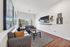 Bright and modern living room with stylish decor, featuring a large wall-mounted TV, cozy gray sofas, and chic wall art, perfect for relaxation and entertainment.