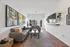 Bright and airy living room with elegant decor, featuring a modern gray sofa, stylish artwork, and a large window offering natural light and inviting views.