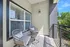 Charming balcony with stylish wicker chairs, modern light fixture, and lush green view, perfect for relaxation.