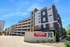Modern apartment building with convenient multi-level parking garage, featuring sleek architecture and vibrant landscaping.